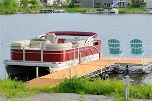 Boat pulled up alongside a dock with two beach chairs.